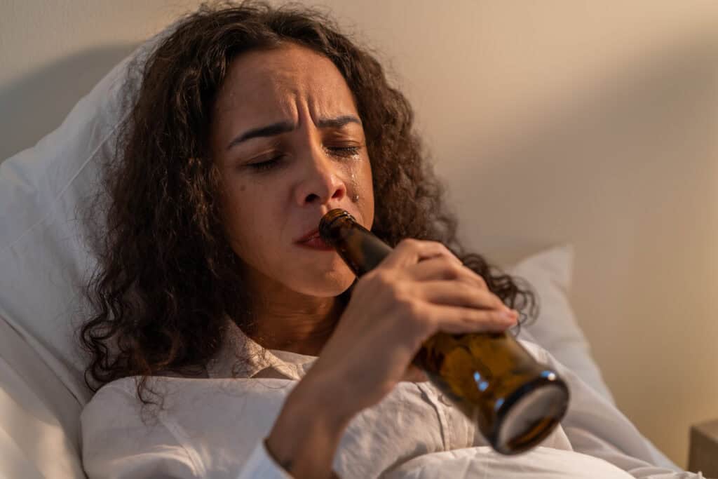 a woman drinking from a bottle during alcohol detox