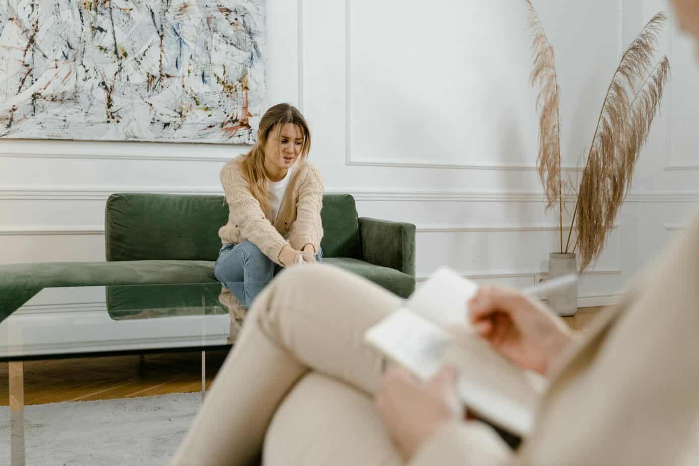 A woman during a therapy session in a modern living room setting, expressing concern.
